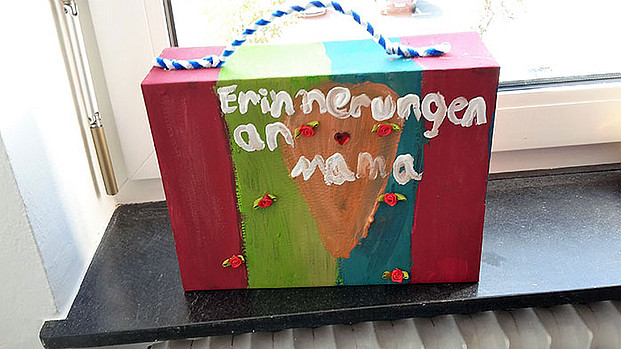 Gebastelter und von Hand bemalter Koffer mit einem Herz und dem Text: "Erinnerungen an Mama"