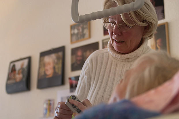 Hospizhelferin hilft beim Einstellen des elektrischen Krankenhausbettes