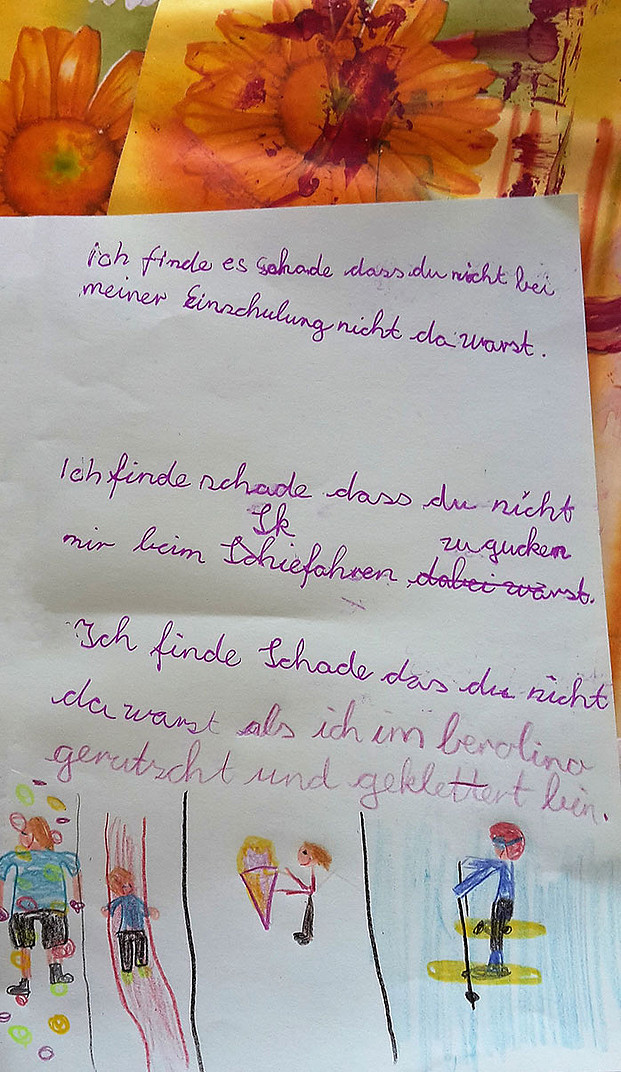 Brief an einen Elternteil mit gemaltem Personen / Kindern beim Skifahren, Eisessen, etc. Text mit Schreibfehlern: "ich finde es schade dass du nicht bei meiner Einschulung nicht da warst. Ich finde schade dass du nicht mir beim Skiefahren zugucken warst. Ich finde Schade das du nicht da warst als ich in berolino gerutscht und geklettert bin."